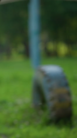 close-up leg view of someone sprinting across three tires, with other tires arranged in the grassy field, with a blurred goalpost and poles in the background