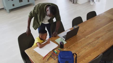 African-american-father-and-son-doing-homework-and-using-a-laptop-together