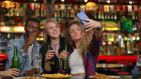 En-El-Bar-O-Restaurante,-Un-Hombre-Hispano-Se-Toma-Un-Selfie-De-Ella-Y-De-Sus-Mejores-Amigos.-Grupo-De-Jóvenes-Hermosos-En-Un-Establecimiento-Elegante.