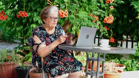 Aged-female-speaking-on-phone-at-table-with-laptop
