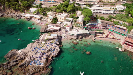 an epic aerial shot rising above stunning beaches and sparkling blue water in marina piccola on capri, a famous island that is a popular luxury vacation destination in italy along the amalfi coast