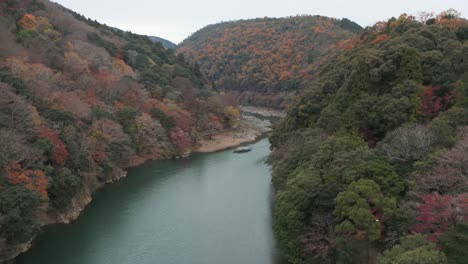 autumn arashiyama canyon as boat travels down katsura river towards kyoto