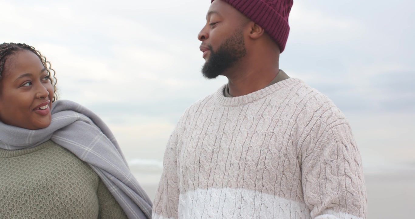 African American couple walking shore male angling phone, wearing beanie preparing handheld capture