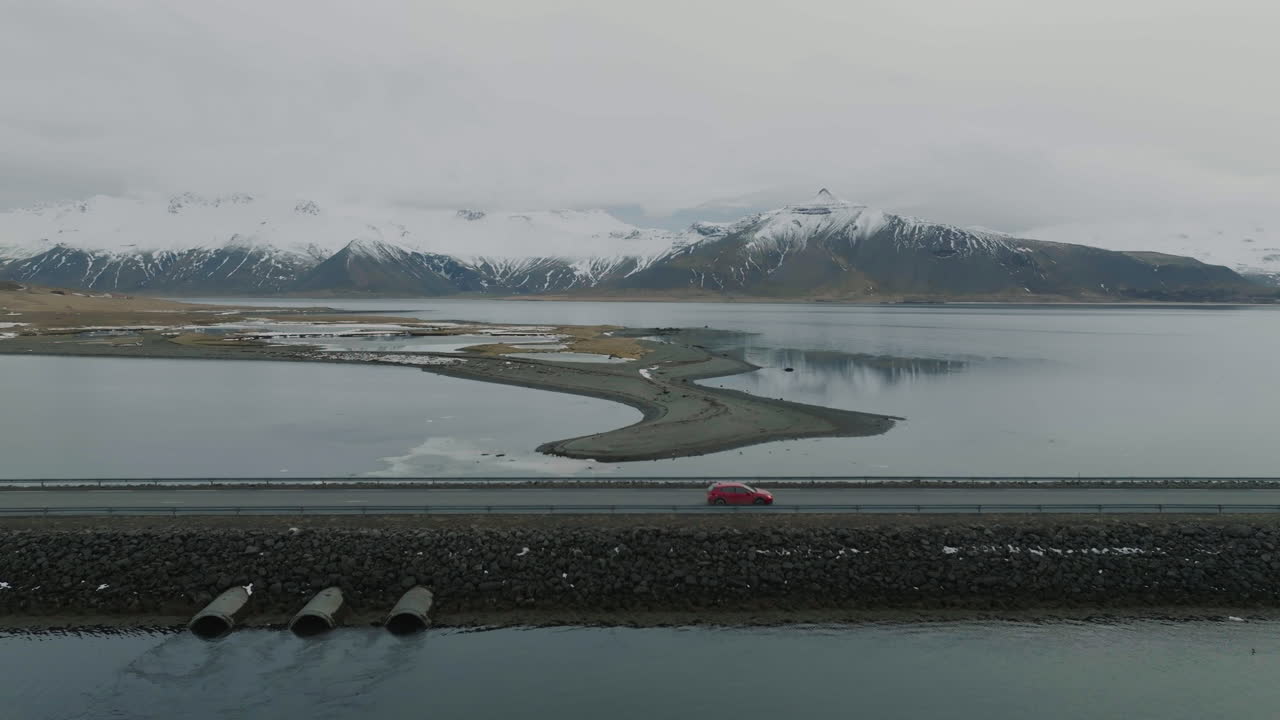 아이슬란드 의 백그라운드 에 눈 이  ⁇ 인 화산 언덕 이 있는 빙하 호수 위 에 있는 길 위 에 움직이는  ⁇ 은 차 의 공중 사진