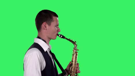retrato de un joven elegante tocando el saxofón en una pantalla verde en el estudio. saxofonista tocando un solo. vista lateral. primer plano