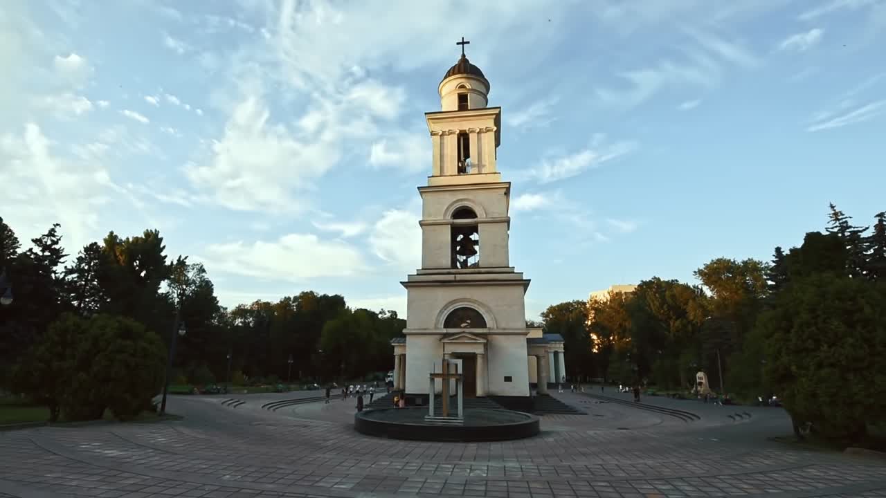 Bell tower and Nativity cathedral in the central park of the city in the evening. Walking people. Slow motion