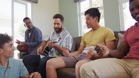 diversos amigos hombres felices tocando la guitarra y hablando en la sala de estar