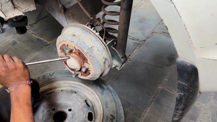 mechanic servicing rear drum brake assembly during routine vehicle maintenance in auto workshop