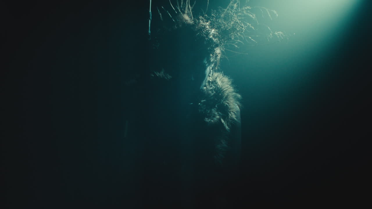 A creepy witch stands in the moody pose during the night storm