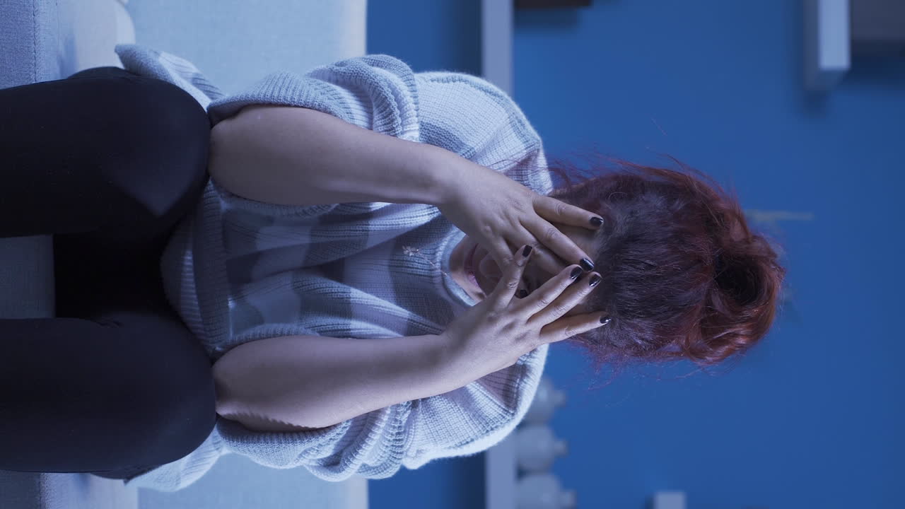 Video vertical de mujer angustiada cubriéndose el rostro con la mano.