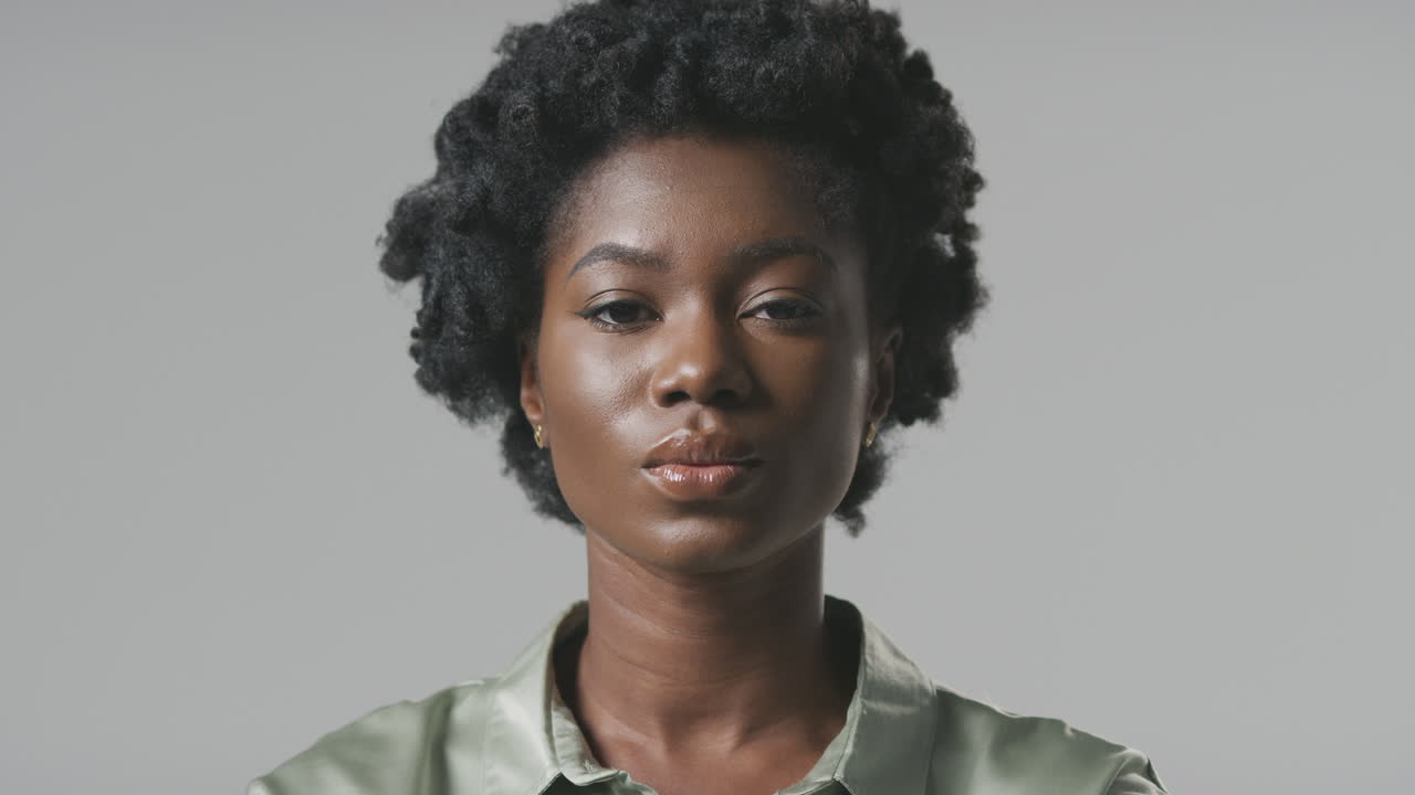 retrato de estudio de una joven mujer de negocios seria volviéndose hacia la cámara frente a un fondo plano