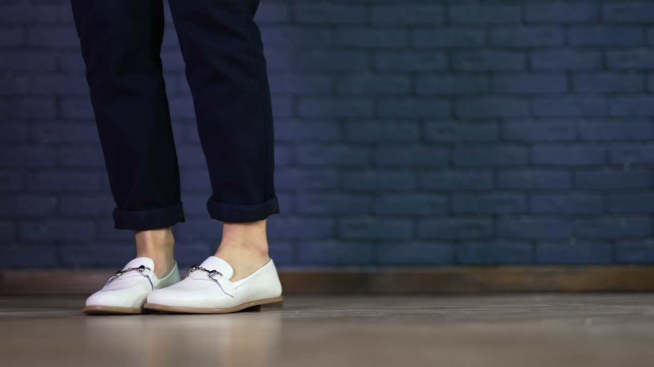 Woman wearing white loafers and black pants