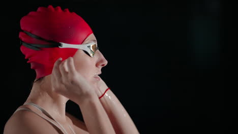 woman in a red swim cap and goggles preparing for swimming