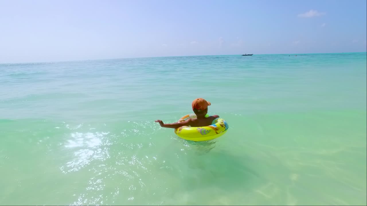 a child swims and plays with his buoy on the beach of jambiani zanzibar