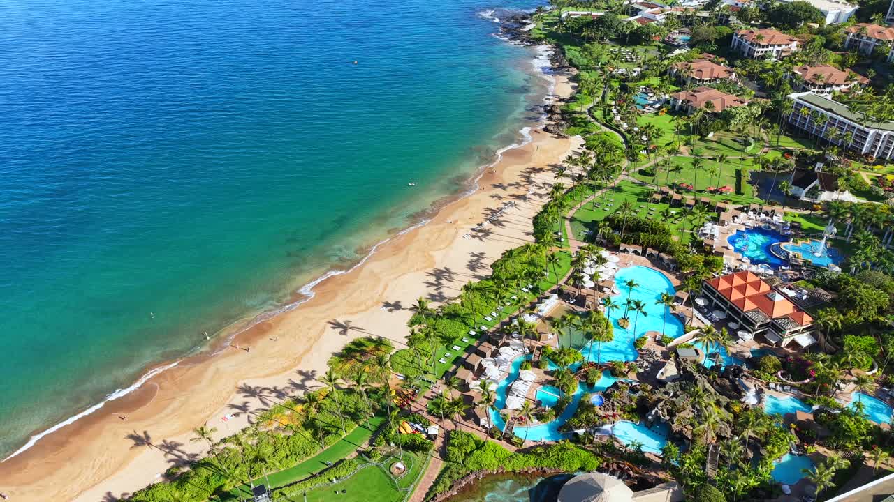 Grand Wailea resort with pools and beach on the sunny coast of Maui, wide aerial view