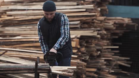 a young man cuts firewood with a chainsaw outdoors