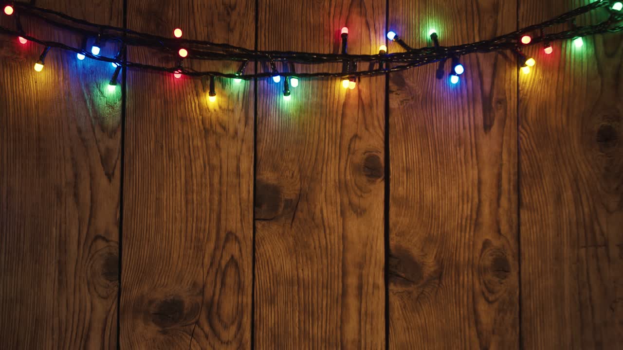 Latar belakang bingkai lampu Natal berulang, karangan bunga realistis di papan kayu pedesaan tua, dekorasi meriah, lampu berwarna hangat yang bersinar dan memudar. Animasi 3D liburan Selamat Natal dan Tahun Baru.