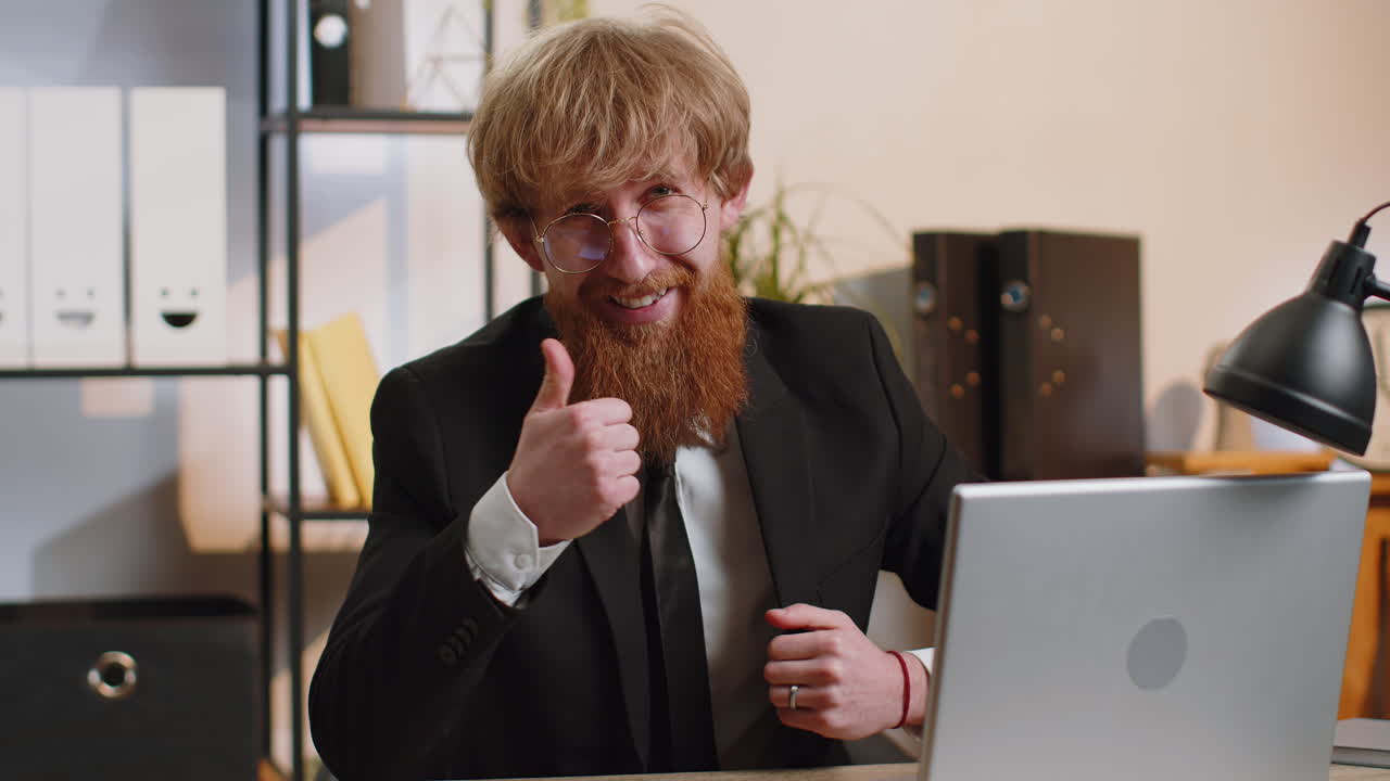 Happy business man looking approvingly at camera showing thumbs up like positive sign good news