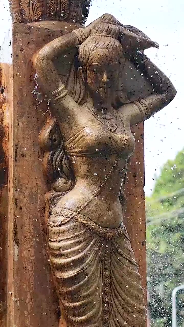 Statue avec un jeu d'eau au cœur d'une verdure luxuriante