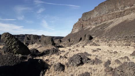 Flying-low-amongst-ancient-weathered-volcanic-basalt-columns,-Dry-Lake-Falls,-Washington,-aerial