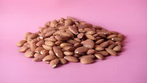 una pila de almendras en un fondo rosa