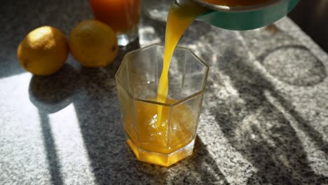 Verter-Jugo-De-Naranja-Recién-Exprimido-En-El-Vaso-Transparente-Vacío---Tiro-Estático-En-ángulo-Bajo