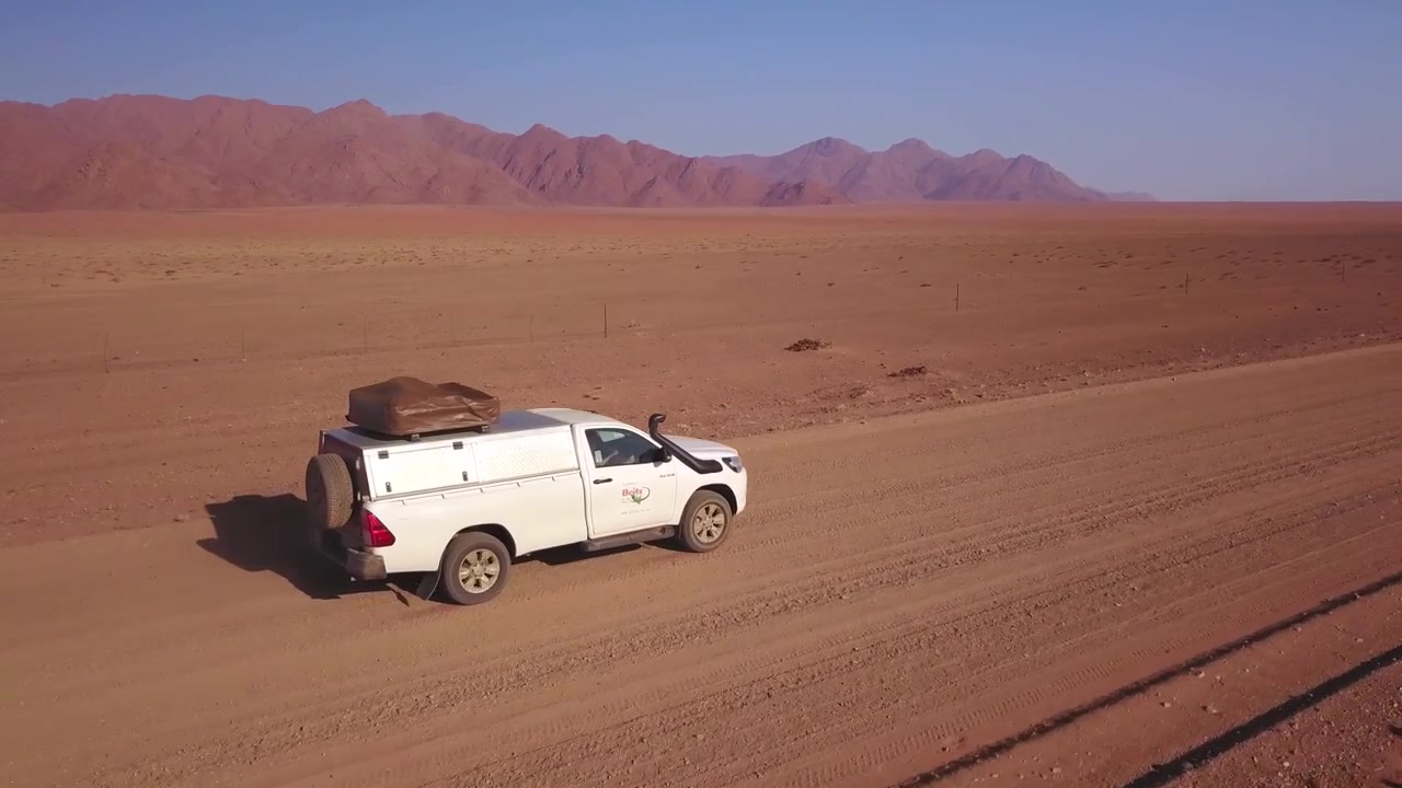 Vista aerea laterale di un'auto che guida su una strada desertica in Namibia