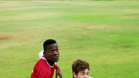 two football players jumping to strike a ball