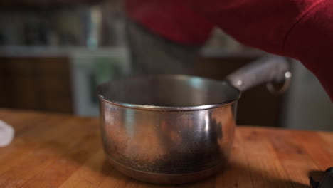 man puts canning jar lids into pot of steaming water for sterilization - close up