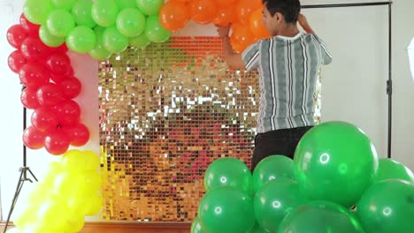 man setting up cinco de mayo festive backdrop with mexican decor