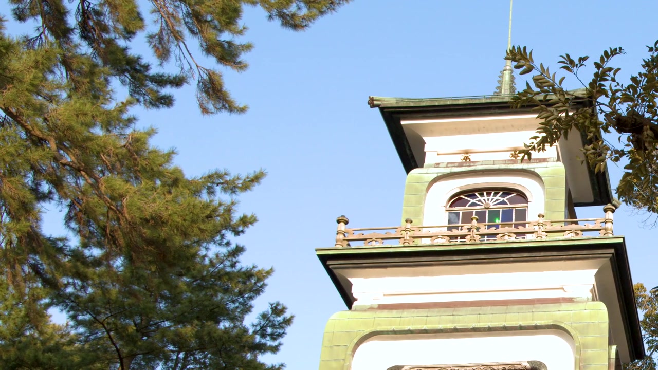 Traditional Japanese Temple Building with Pine Tree Branches Against Blue Sky