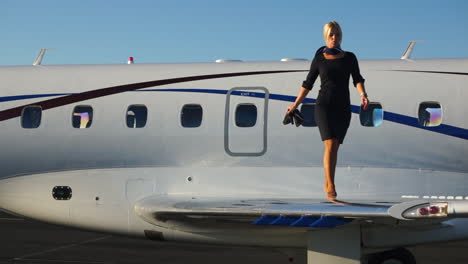 a playful flight attendant walks on the wing of an aircraft