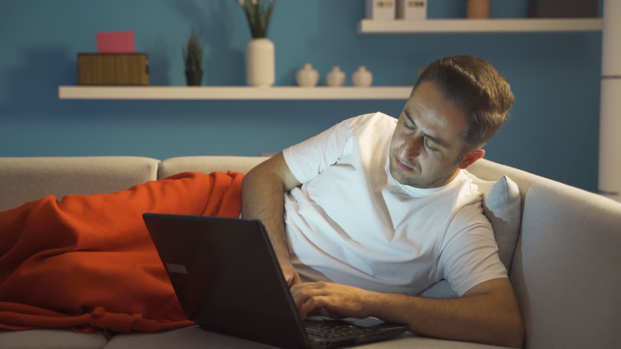 hombre cansado y agotado usando una computadora portátil acostado.
