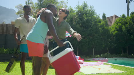 diverse friends enjoying sunny day by pool, setting up picnic with cooler and towels