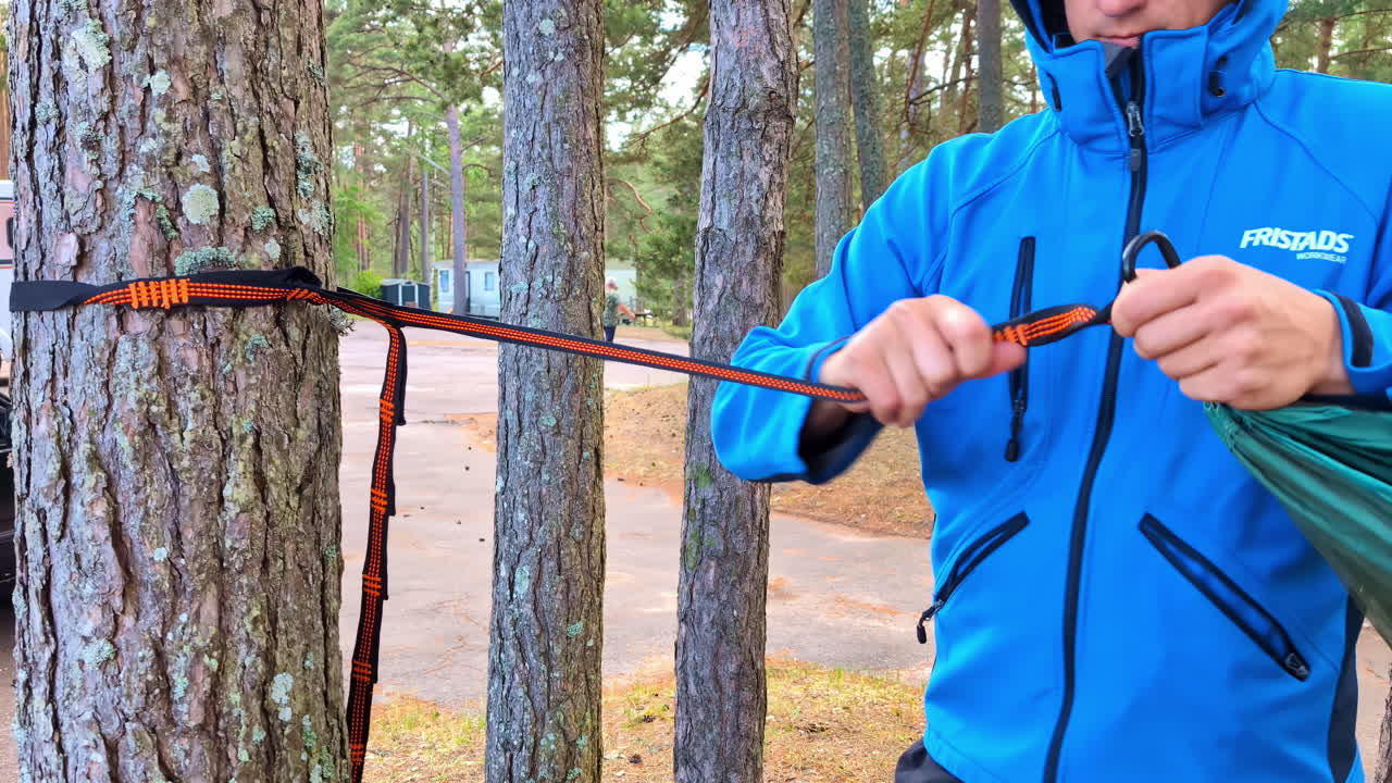 Man fastening tree hammock in local woodland