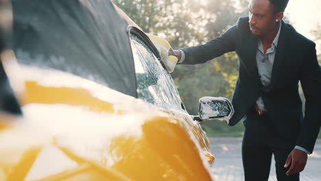 hombre lavando un coche descapotable amarillo