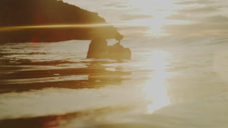 glistening sunset light spreads rays across ocean surface as photographer adjusts camera settings in water