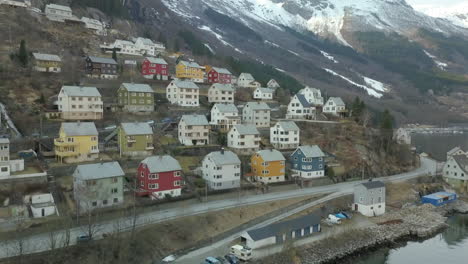 aerial view flying towards the colorful houses in the small town of odda, norway located right next to a fjord