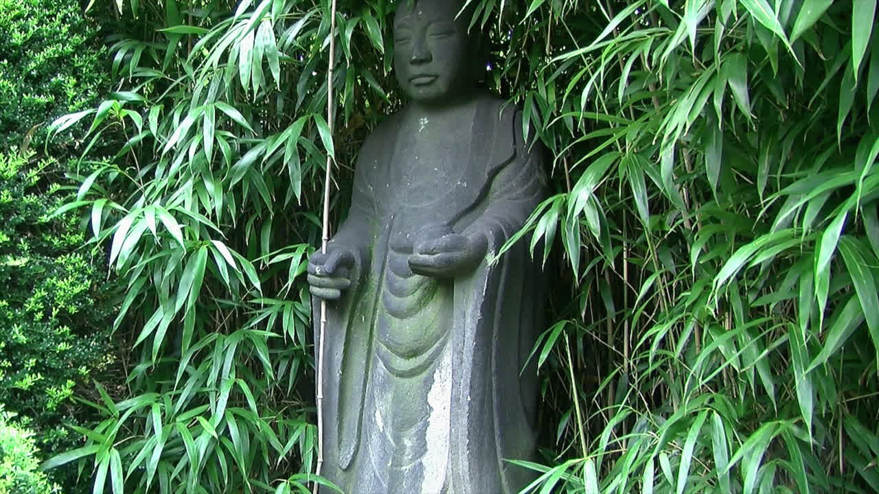 inclínate sobre la estatua de jizo en un jardín japonés