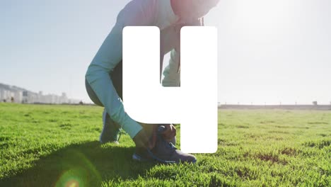 animation of countdown over biracial woman tying shoes in park