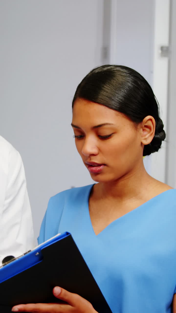 Nurse and doctor discussing over clipboard