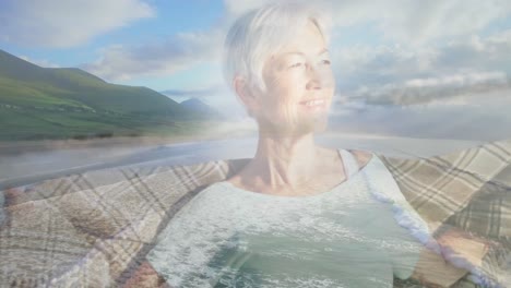 animation of glowing light over smiling senior woman by seaside