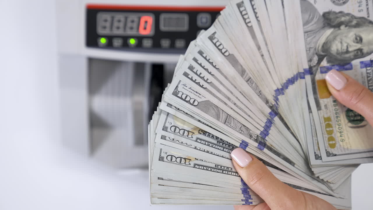 Hundred dollar bills in female's hands. Much american paper money in hands on the background of electronic calculating machine. Close-up.