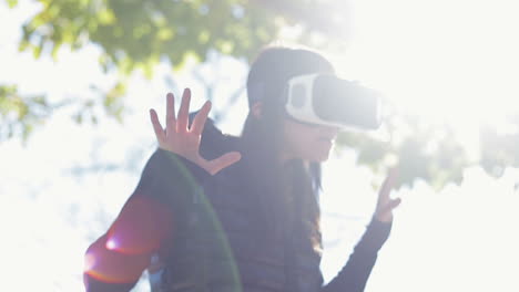 Amazed-young-dark-haired-woman-in-warm-black-waistcoat-wearing-virtual-reality-glasses-in-early-autumn-park