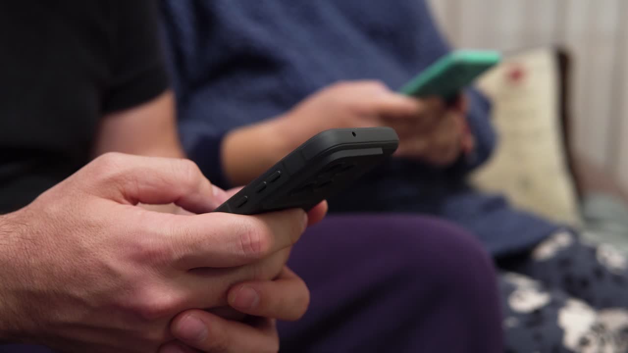 Coppia che usa smartphone seduta insieme. L'impatto del tempo trascorso davanti allo schermo sulle relazioni moderne