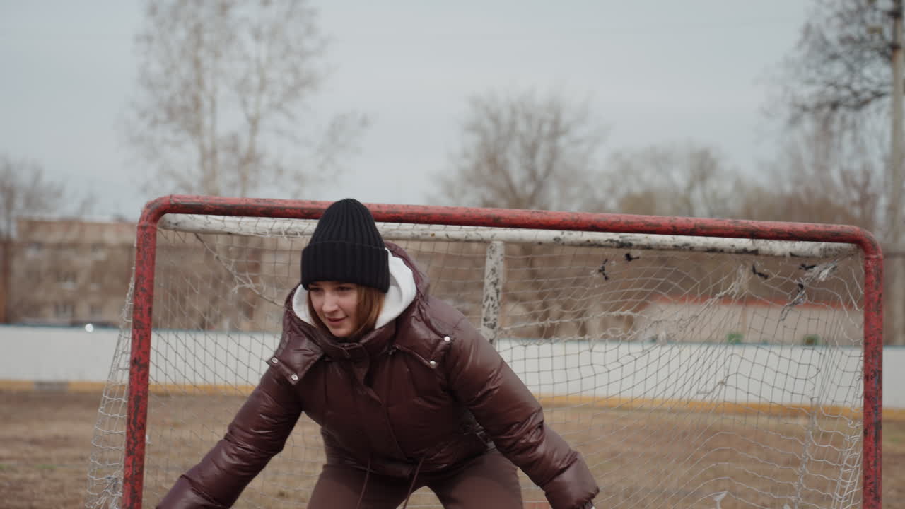 Радующаяся спортсменка празднует победу: счастливая спортсменка ликует от радости, женщина в зимней экипировке торжествует на поле, радостная спортсменка выражает триумф, празднуя победу на открытом воздухе в зимних условиях