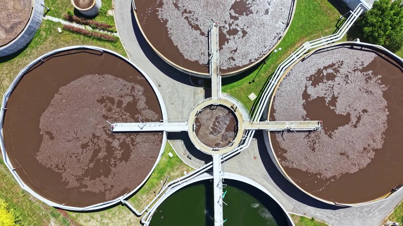 Las instalaciones de tratamiento de aguas residuales funcionan para limpiar el agua en una planta municipal ubicada en un área urbana durante un día soleado.
