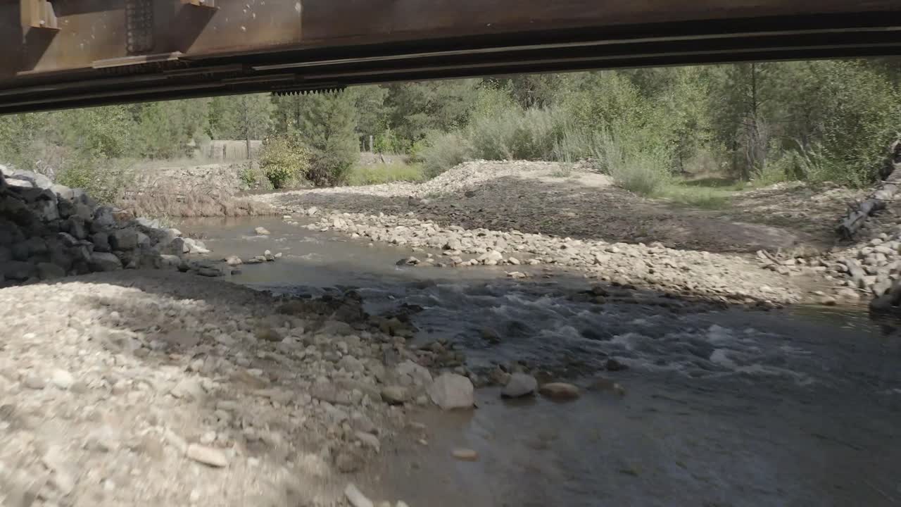 개울 위의 다리 아래에서 빠른 비행의 공중 드론 샷