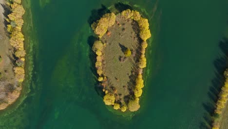 Top-down-of-lake-island-with-yellow-trees-during-autumn-season,-New-Zealand