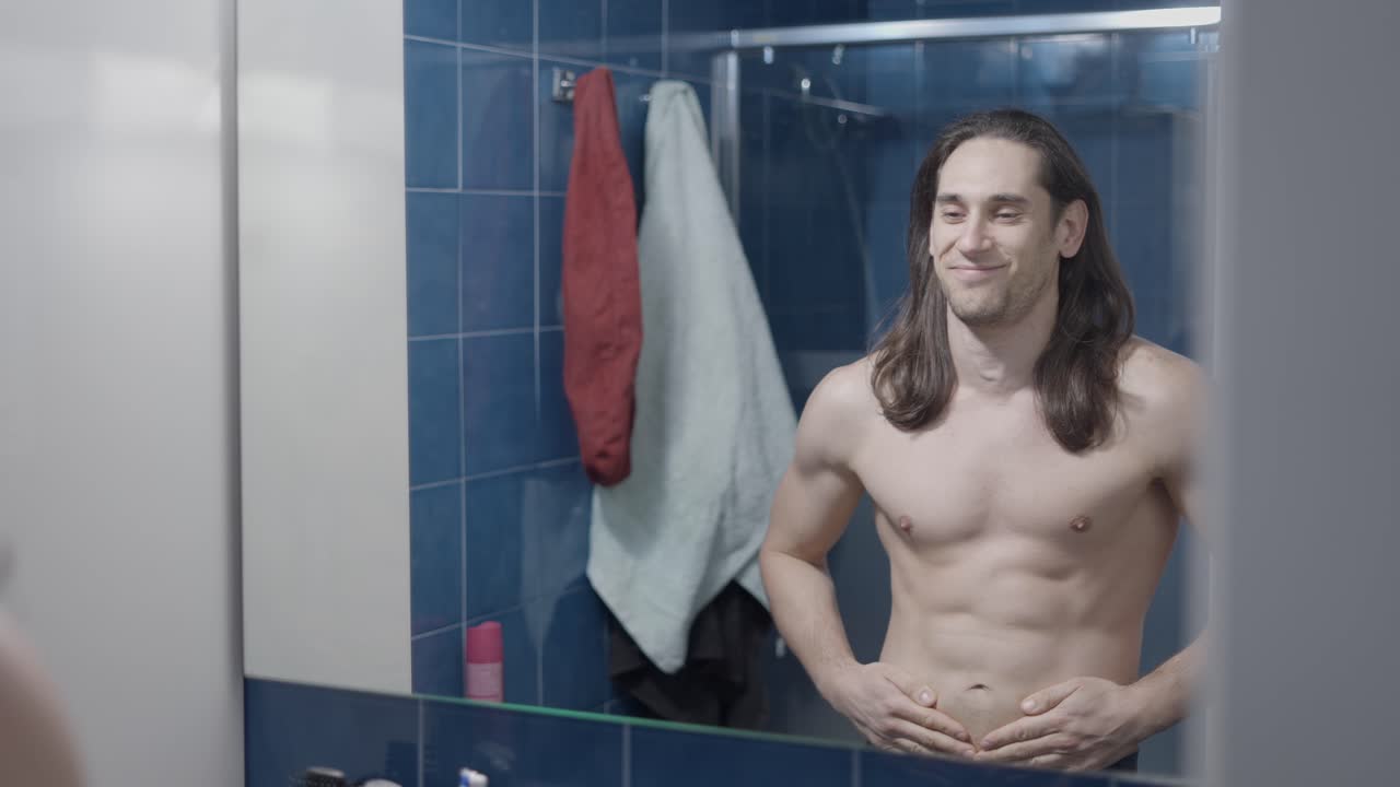 Man Checking Body in Bathroom Mirror